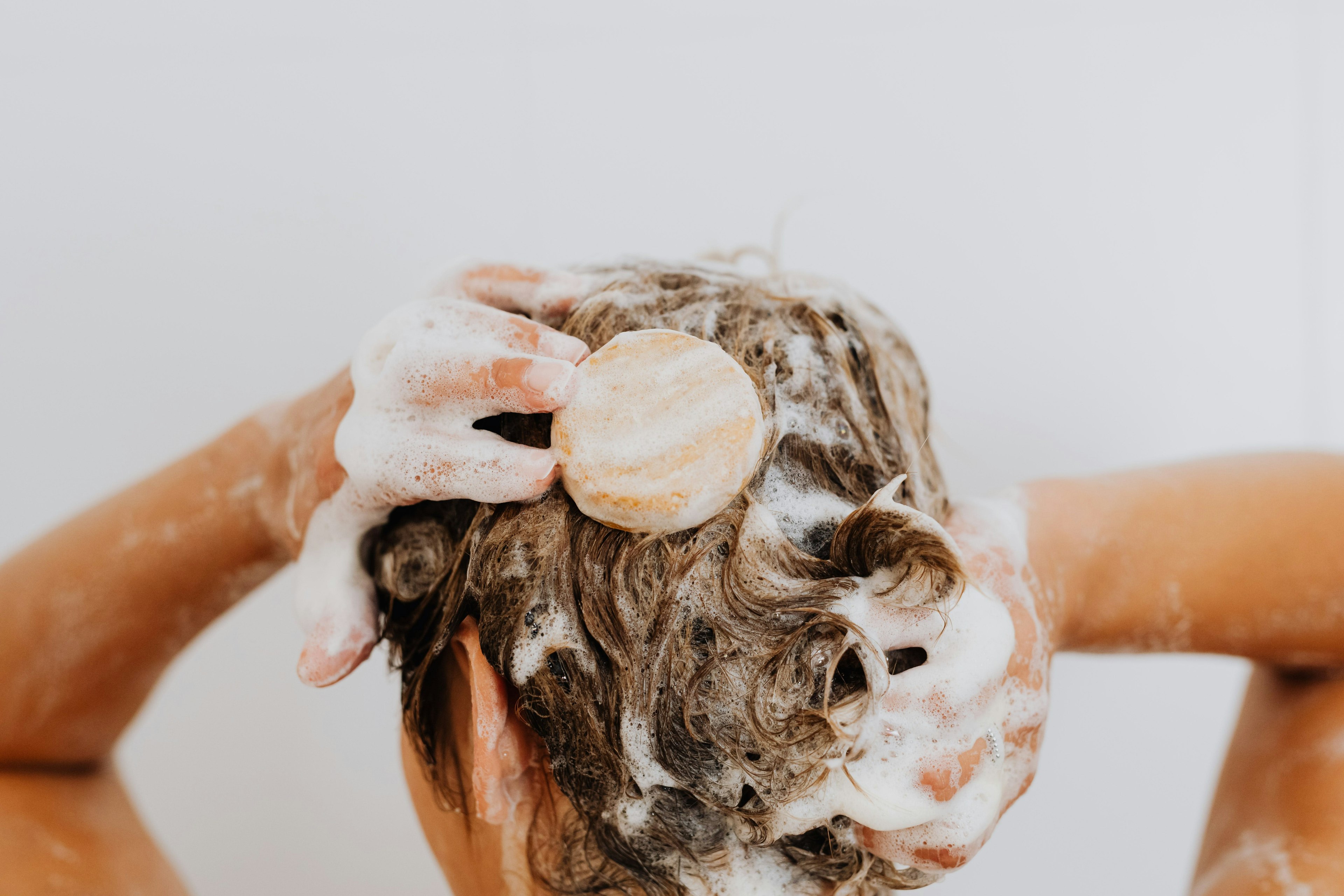 Femme qui se lave les cheveux avec shampoo solide